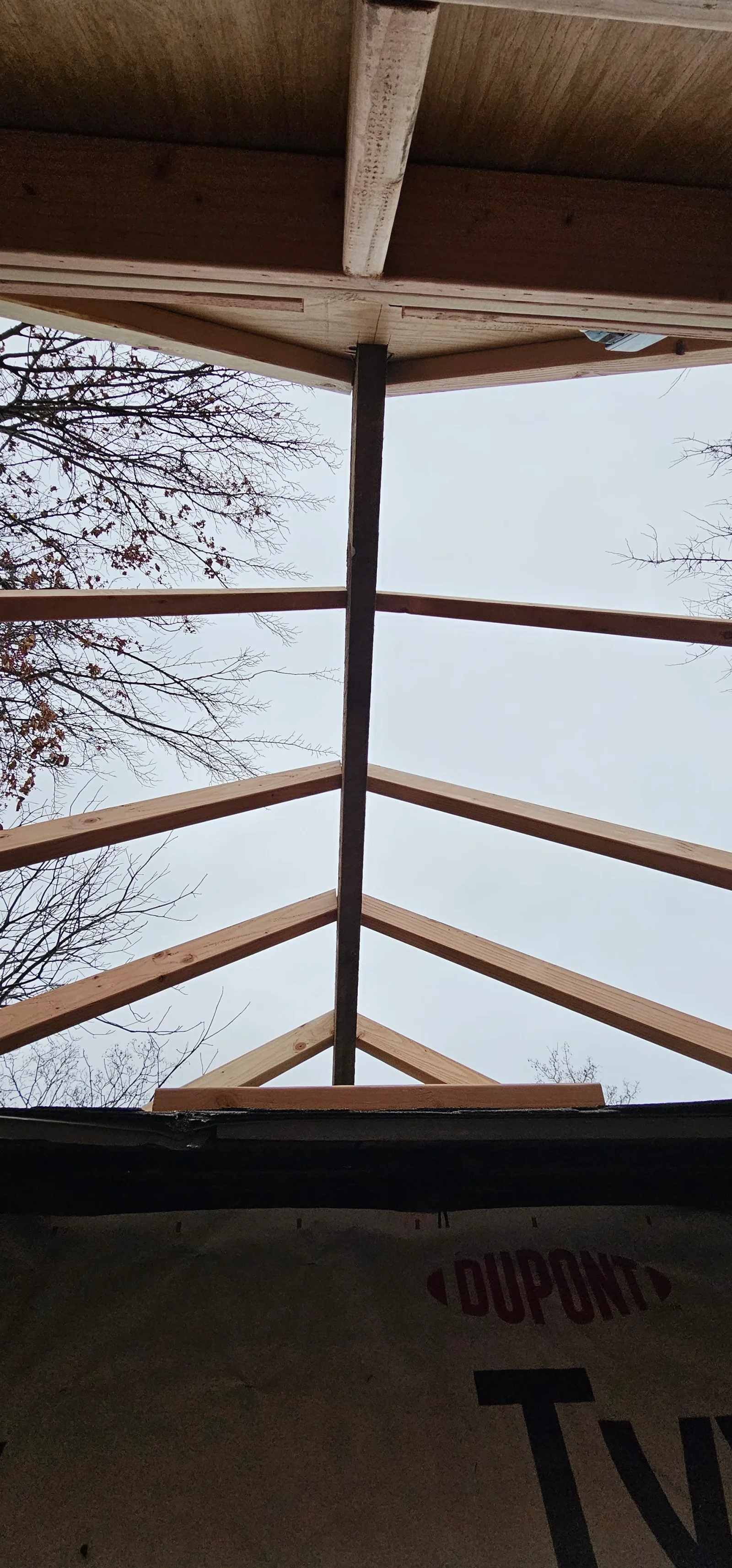 Timber frame pergola with wooden beams and central post, open-air construction