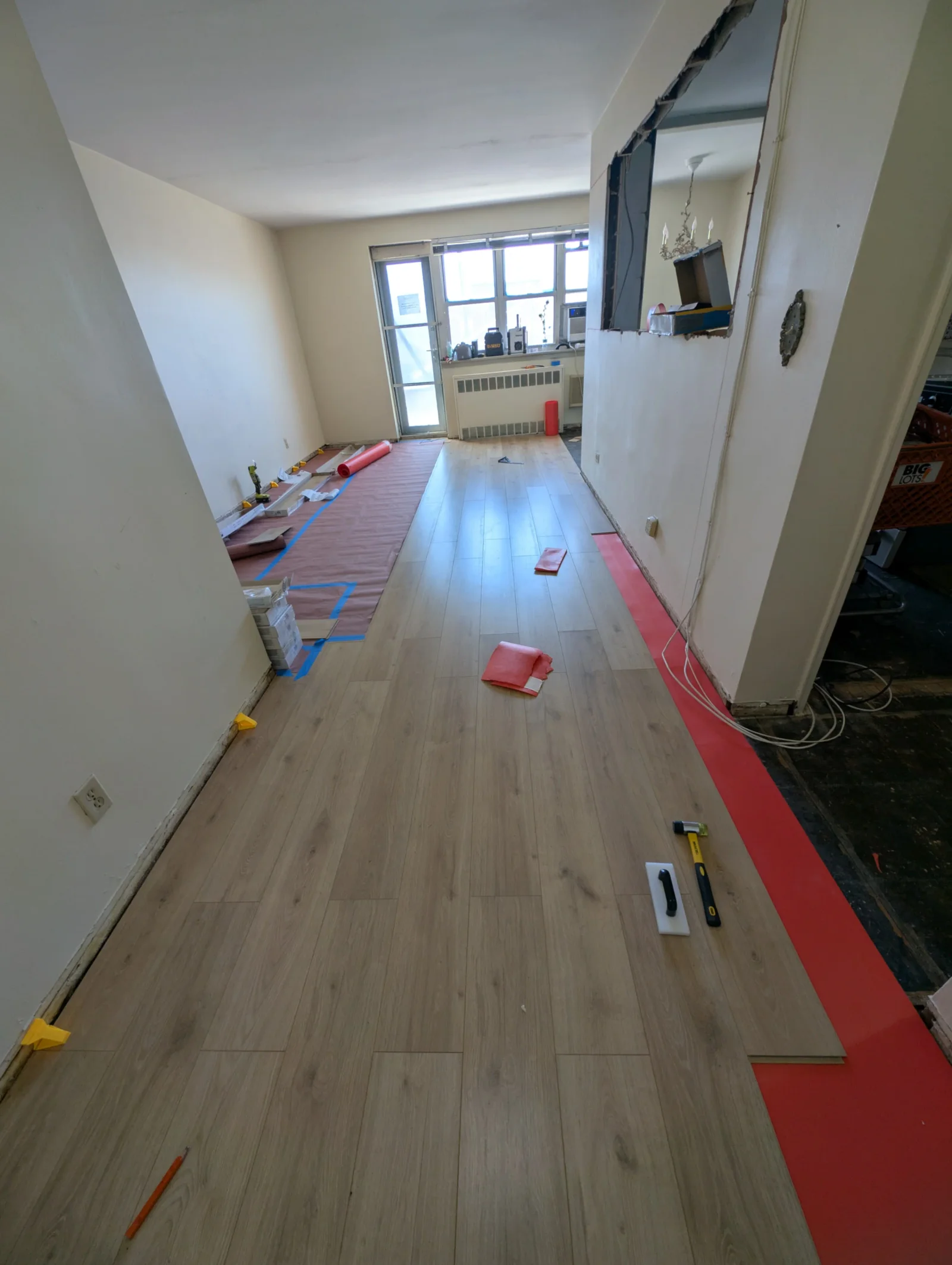 Luxury vinyl plank flooring installation with blue underlayment and protective tape in progress
