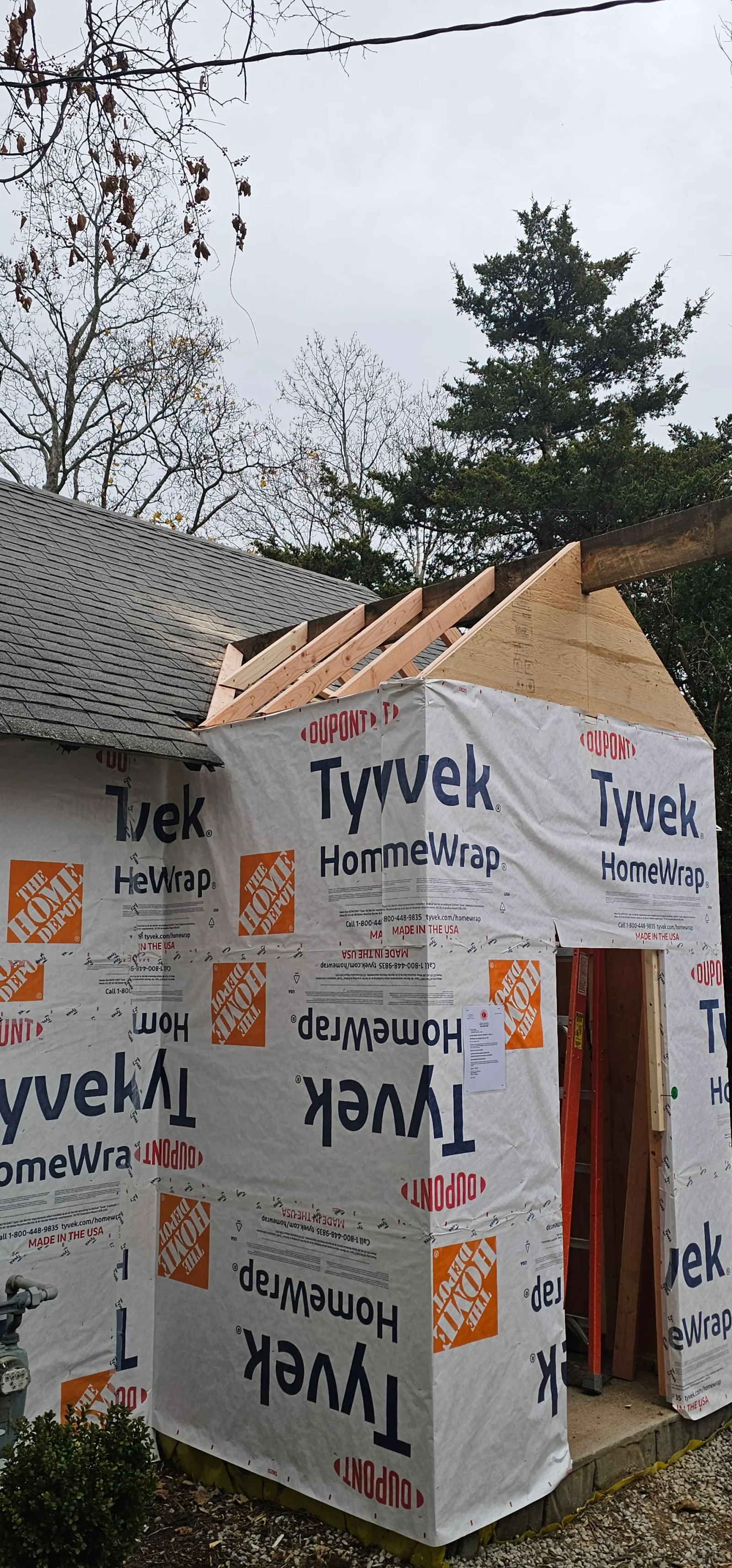 Wood framed addition with Tyvek HomeWrap weather barrier and roof trusses under construction